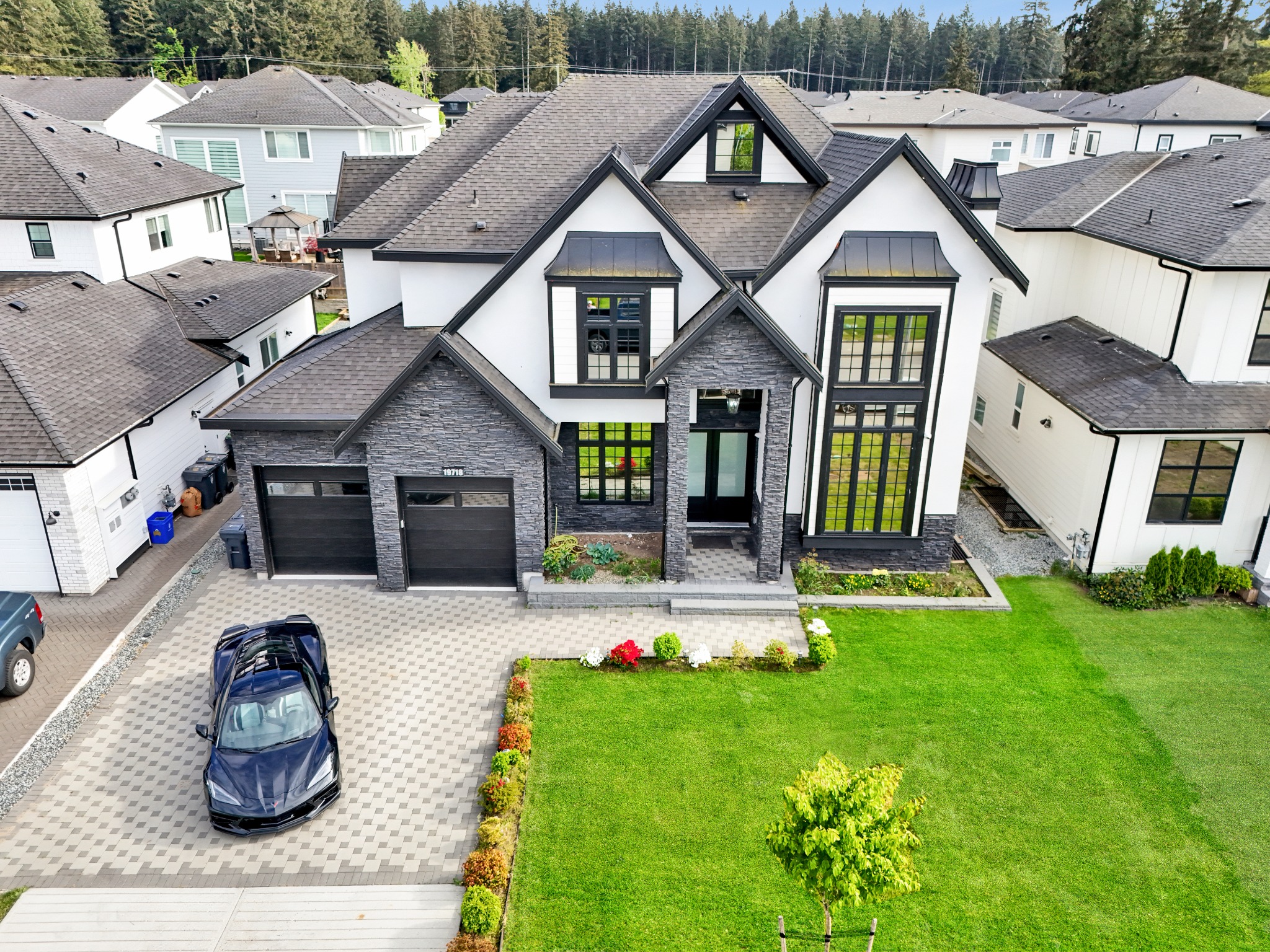 Contemporary white and charcoal home with stone cladding, tall windows and landscaped gardens